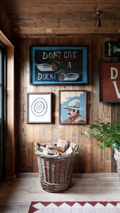 a room with wooden walls and pictures hanging on the wall, along with a basket full of wood chips