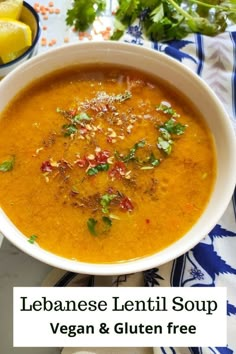 a white bowl filled with soup on top of a blue and white table cloth next to lemons