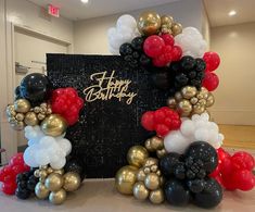 a happy birthday balloon arch with red, white and black balloons