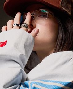 a woman wearing glasses and a hat is talking on her cell phone