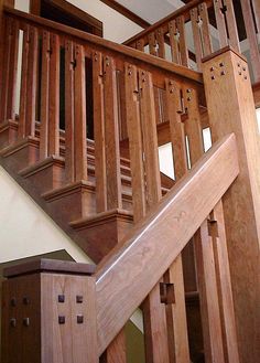 a wooden stair case in a house with wood balconies and handrails