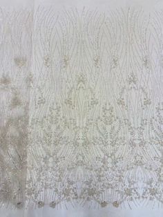 two white curtains with silver and gold designs on the top one is open to reveal an intricate pattern