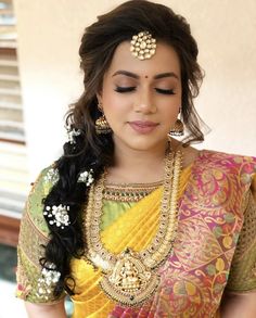 a woman wearing a yellow and green sari with gold jewelry on her head, looking down