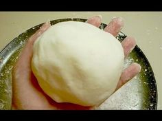 a hand holding a ball of dough on top of a metal pan with sugar sprinkles