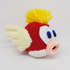 a crocheted red fish with yellow hair and blue eyes on it's head