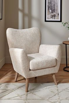 a white chair sitting on top of a hard wood floor next to a table with a potted plant