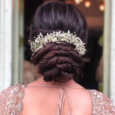 the back of a woman's head wearing a braid and flowers in her hair