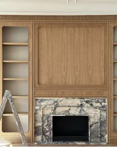 a living room with marble fireplace and built in bookcases on either side of the fireplace