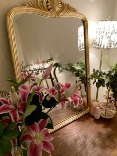 a mirror sitting on top of a wooden table next to a vase with flowers in it