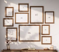 there are many frames on the wall with numbers and flowers in vase next to them