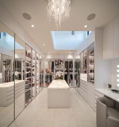 a room filled with lots of white furniture and chandelier hanging from the ceiling