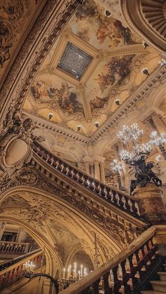 an ornate staircase with chandeliers and paintings on the ceiling