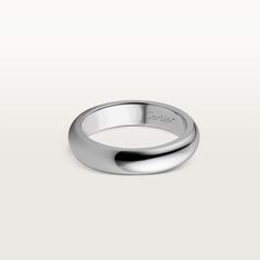 a white gold wedding ring on a plain surface