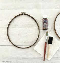 some crafting supplies are laying out on a white wooden surface, including paint and scissors