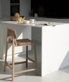 a kitchen island with a wooden stool and bowl of fruit on the counter next to it