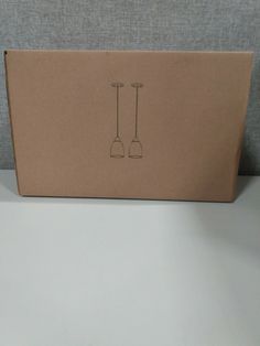 a cardboard box with two spoons drawn on the front and back of it, sitting on a table