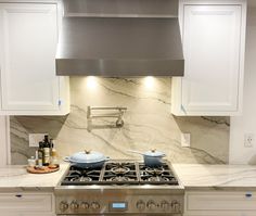 a stove top oven sitting inside of a kitchen next to white cabinets and counter tops