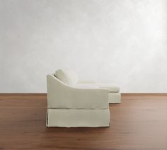 a white couch sitting on top of a hard wood floor next to a chair and ottoman