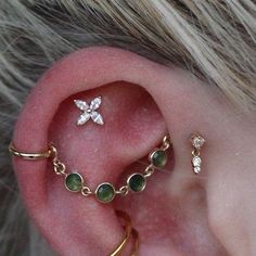 an ear with three different types of piercings on top of it and one is attached to