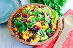 a wooden bowl filled with black beans, corn and cilantro