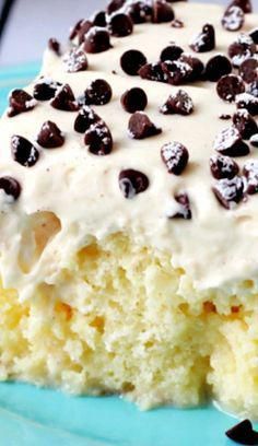 a piece of cake with white frosting and chocolate chips on top sits on a blue plate