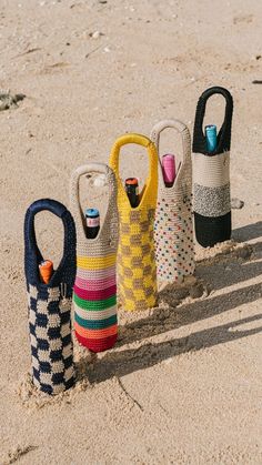 four different colored bags sitting in the sand