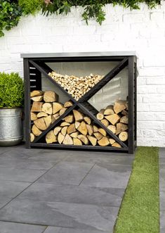 a firewood rack with logs in it on the ground next to a potted plant