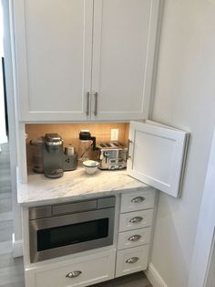 a kitchen with white cabinets and silver appliances