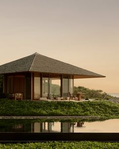 a small house sitting on top of a lush green field next to a body of water