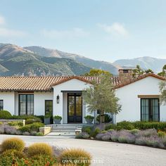 this is an image of a house in the hills with flowers and bushes around it