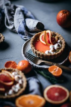 an orange tart topped with whipped cream and sliced up blood oranges on a table