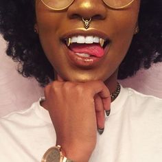 a woman with gold makeup and glasses on her face is posing for the camera while holding her hand to her chin