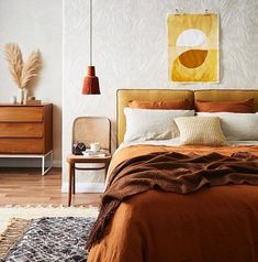 a bedroom with a bed, nightstands and paintings on the wall behind it in shades of brown