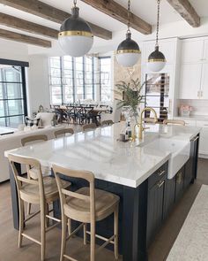 a large kitchen with an island in the middle and two pendant lights hanging from the ceiling