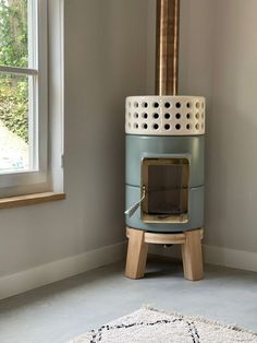 a blue stove sitting in the corner of a living room next to a white rug