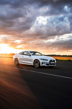 a white car driving down the road at sunset