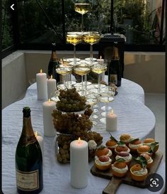 a table topped with lots of food next to wine glasses and candles on top of it