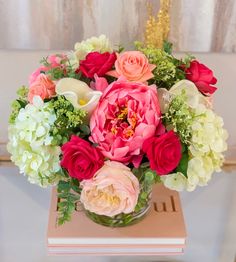 a vase filled with lots of flowers on top of a wooden table next to a book