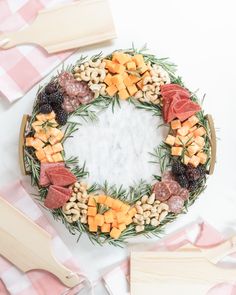 a platter filled with meats, cheeses and other foods on top of a pink checkered table cloth