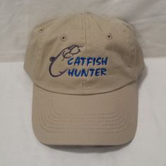 "Embroidered \"Catfish Hunter\" design hat Great hat for Fishermen, a Father's Day gift, a Birthday gift, a Christmas gift, or just for plain fun! This is a brand new quality hat and will be embroidered at the time you order it. This hat will be embroidered in our office right in here in the USA and is NOT a cheap / lightweight overseas embroidered hat. Hat color is Khaki, and the embroidery will be sewn in the colors shown in the pictures. Hat Details: - Low Profile - Garment Washed Cotton Twil Hunter Design, Fish Embroidery, Tactical Hat, Fisherman Gifts, Embroidered Gifts, Hook And Loop Tape, Embroidered Hat, Fishing Hat, Quality Hats