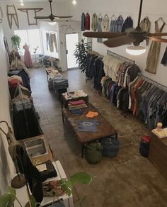 a clothing store with clothes hanging on the walls and tables in front of them,