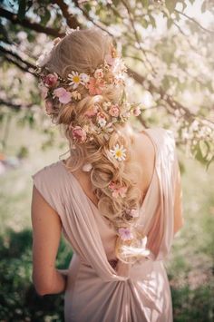 a woman with long hair and flowers in her hair is standing under a tree branch