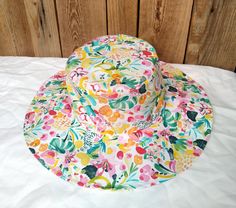 Cotton sun hat made of soft organic cotton. Decorated with a multi-colored floral print, it will fit almost any spring-summer stylization.  Summer hats should be useful, stylish, lightweight and breathable. The hat available in our offer fits perfectly into these aspects, it is an element of clothing that protects the head from the hot rays of the sun. Hat made of airy, certified cotton poplin. The brim of the hat is slightly stiffened, which facilitates modeling. However, this does not prevent Cotton Bucket Hat For The Beach, Cotton Sun Hat Cap For Vacation, Cotton Vacation Cap Sun Hat, Cotton Cap Sun Hat For Vacation, Playful Handmade Sun Hat For Summer, Spring Multicolor Bucket Hat With Uv Protection, Multicolor Uv Protection Bucket Hat For Spring, Tropical Multicolor Spring Hats, Playful Cotton Sun Hat Cap