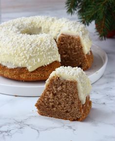 a cake with white frosting sitting on top of a plate next to a christmas tree