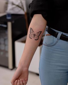 a woman's arm with a butterfly tattoo on the left side of her arm