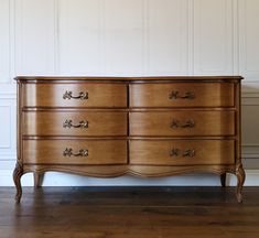 a wooden dresser with many drawers on it's sides, in front of a white wall