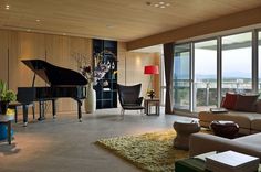 a living room filled with lots of furniture and a grand piano in front of large windows