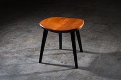 a small wooden table sitting on top of a cement floor next to a black wall