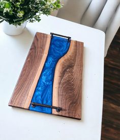 a wooden board with blue glass in the center on a table next to a potted plant