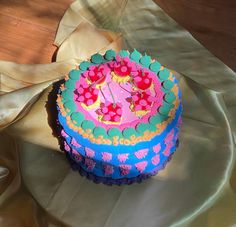 a decorated birthday cake sitting on top of a table next to a ribbon and napkin